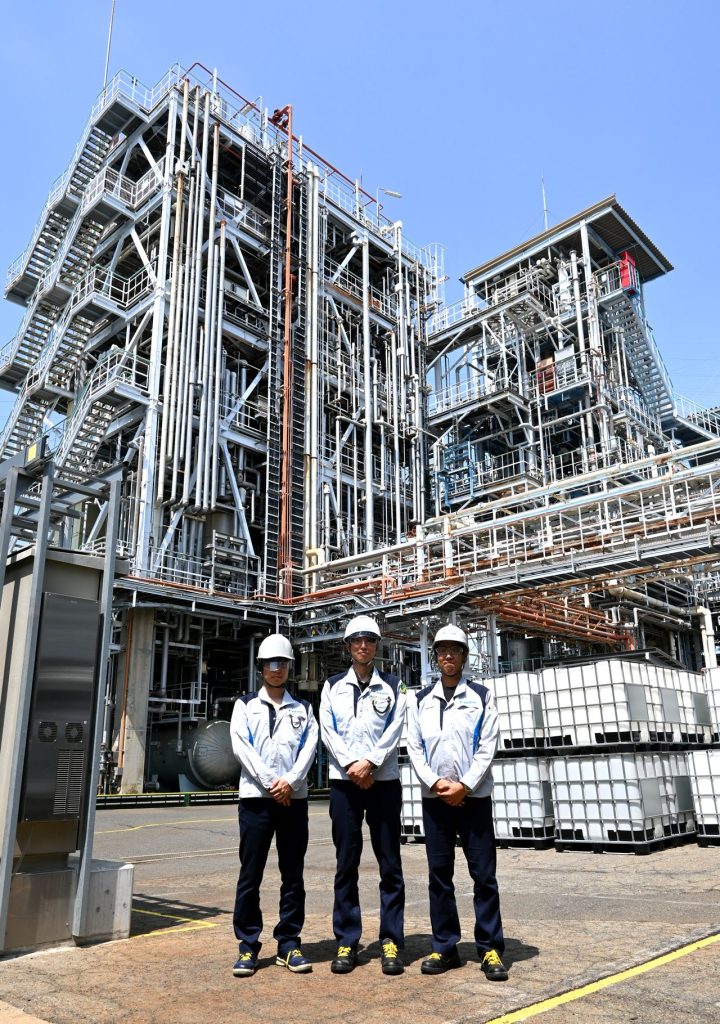 ダイキン工業 化学事業部の岡本様・村田様・青谷様。プラントを背景にした取材集合写真。IoTセンサ導入による業務効率化の事例。